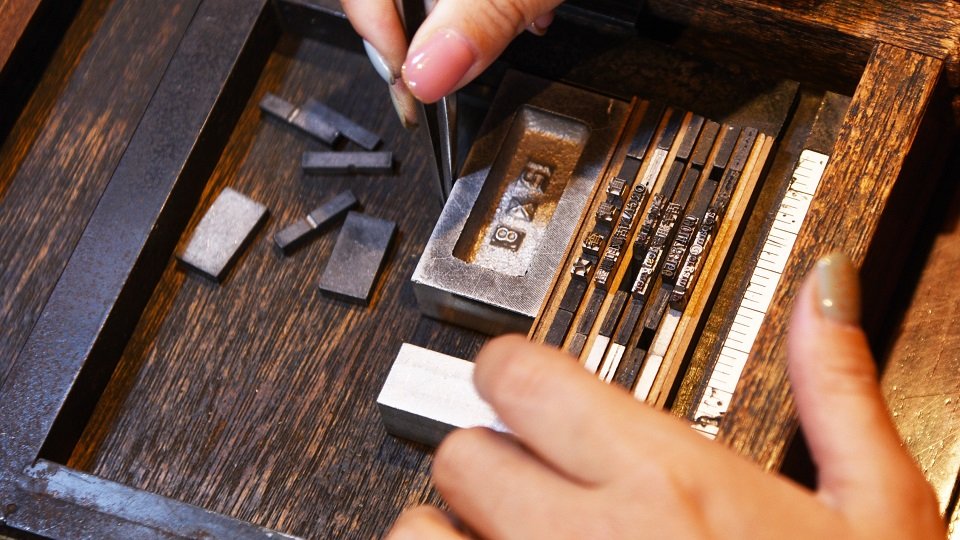 「チェース」と呼ぶ枠の中に活字を組み付ける。大小さまざまな部品を差し込みながら、レイアウトを整えていく＝岐阜市湊町、ＯＲＧＡＮ活版印刷室