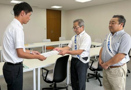 　福井県美浜町役場で、町職員（左）に要望書を提出する原告団長の中島孝さん＝２１日午前