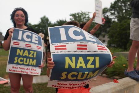 　移民・税関捜査局（ＩＣＥ）に抗議し、「ＩＣＥはナチ、クズ」とのプラカードを掲げる人たち＝１４日、メーン州ビデフォード（ロイター＝共同）