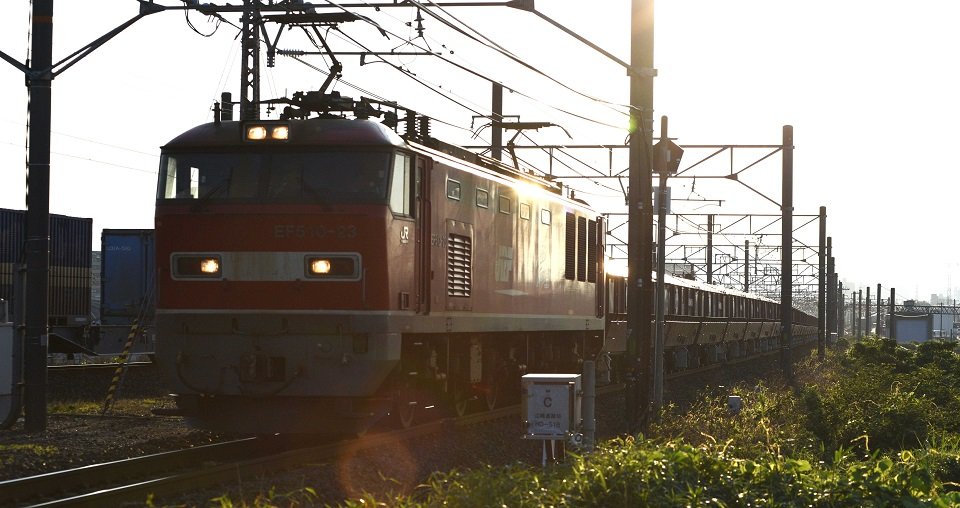 朝日をバックにして、大垣市の美濃赤坂駅へと疾走する石灰石輸送列車。＝岐阜市今嶺