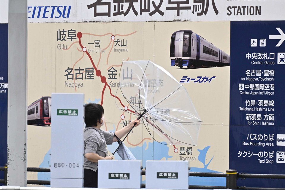 台風７号接近に伴う風で傘が飛ばされそうになる人の姿も＝１５日午前９時５７分、岐阜市神田町