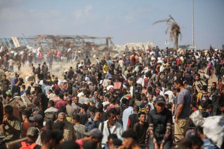 　３１日、ガザ中部で、配給拠点に殺到し、受け取った支援物資を運ぶパレスチナ人ら（ロイター＝共同）