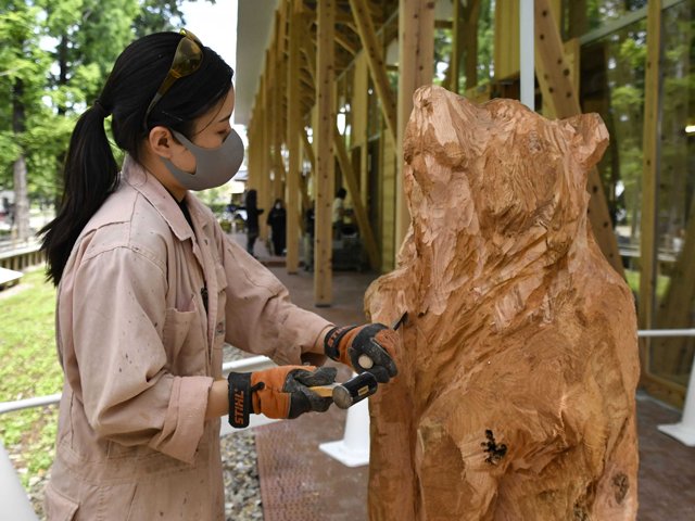 高さ１５０センチほどの熊の木彫作品を仕上げる望月鮎佳さん＝各務原市那加雲雀町、カカミガハラパークブリッジ