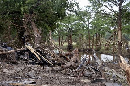 　米テキサス州カー郡イングラムの川沿いに散乱した木やがれき＝９日