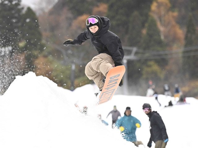 紅葉の山を背景に初滑りを楽しむスノーボーダー＝１２日午前１１時１３分、郡上市白鳥町、ウイングヒルズ白鳥リゾート