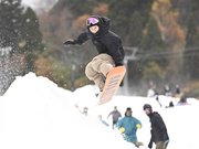 紅葉の山を背景に初滑りを楽しむスノーボーダー＝１２日午前１１時１３分、郡上市白鳥町、ウイングヒルズ白鳥リゾート