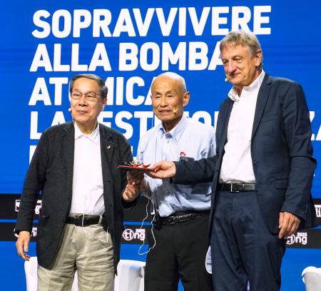 　イタリア・リミニのイベントで登壇した箕牧智之さん（中央）と朝長万左男さん（左）＝２５日（共同）