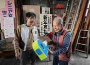 思い出の作品のレプリカを津田社長（左）から渡され、「よく出来てるなあ」と感心する伊神鈞さん