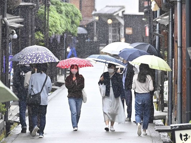 小雨の中、傘を差して古い町並みを歩く人たち＝１６日午前１０時４２分、高山市上三之町