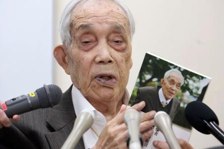 　「被爆者　森下弘の証言」を手にする森下弘さん＝４月、広島市