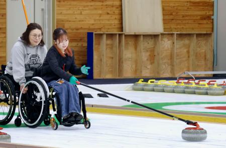 　車いすカーリングの体験会で、ストーンを滑らせる参加者＝５日午後、札幌市