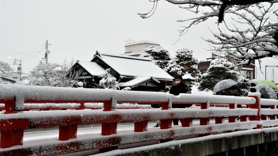 高山市の赤い中橋で雪景色を撮影する人＝１８日午前１０時５６分