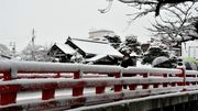 高山市の赤い中橋で雪景色を撮影する人＝１８日午前１０時５６分