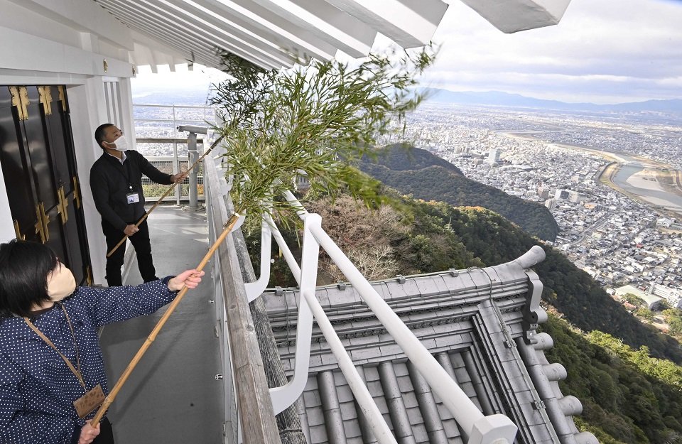 天守の軒裏のすすを払う市職員＝１５日午前９時５６分、岐阜市、金華山山頂の岐阜城