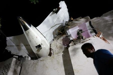 　エア・インディア機の墜落現場に残る機体の一部の近くを歩く人＝１２日、インド・アーメダバード（ロイター＝共同）