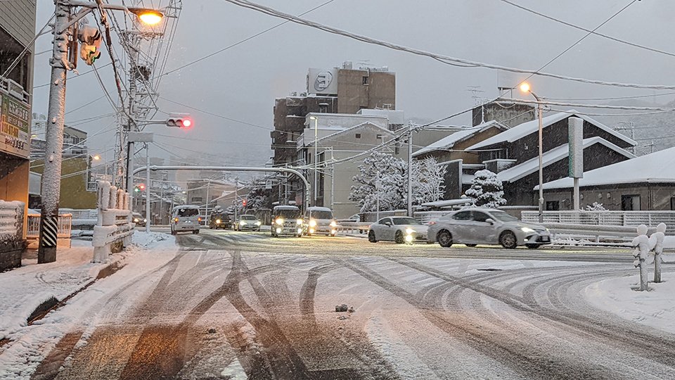 雪が降る中、スピードを落として走る車＝１４日午前６時５６分、岐阜市内