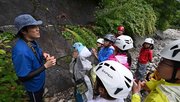 足跡化石の露頭の前で解説する高津翔平さん（左）＝大野郡白川村