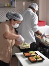 感染防止で中止している会食の代わりに弁当を作り、容器に詰めるスタッフ＝２日午前１０時１８分、同教会