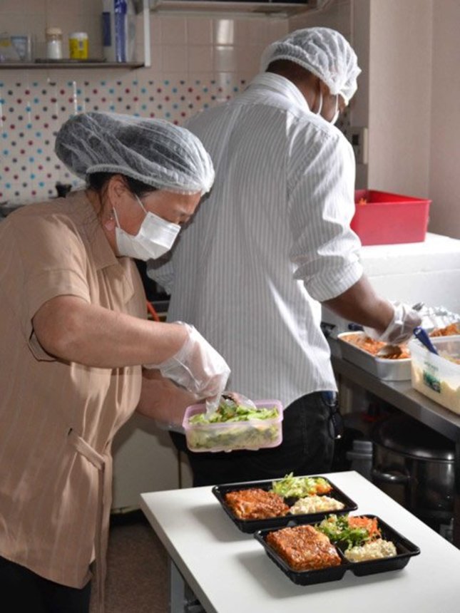 感染防止で中止している会食の代わりに弁当を作り、容器に詰めるスタッフ＝２日午前１０時１８分、同教会