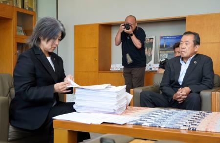 　早期辞職を求める署名を受け取り、確認する静岡県伊東市の田久保真紀市長。右は元市議の浜田修一郎さん＝２７日午前、伊東市役所
