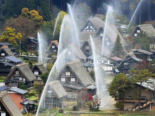 合掌造り集落を水のカーテンで覆った一斉放水訓練＝７日午前８時２分、大野郡白川村荻町
