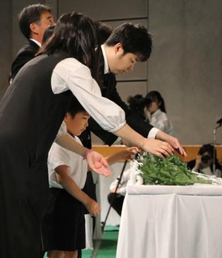 　戦没者追悼式で若い世代を代表して献花する遺族ら＝１５日午前、松山市