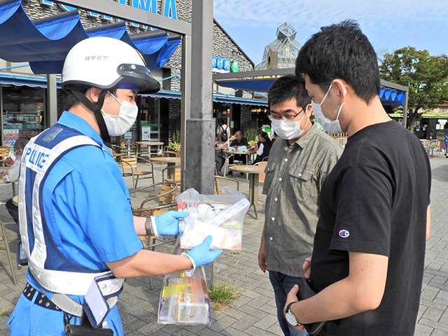 高速道路利用者にチラシを配布する県警高速隊員＝各務原市川島笠田町、川島パーキング