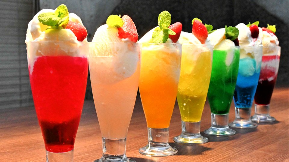 虹色に輝くクリームソーダ。手前からストロベリー、桃、みかん、パイナップル、メロン、ブルーハワイ、ぶどう＝大垣市新田町、亜蛮忠留