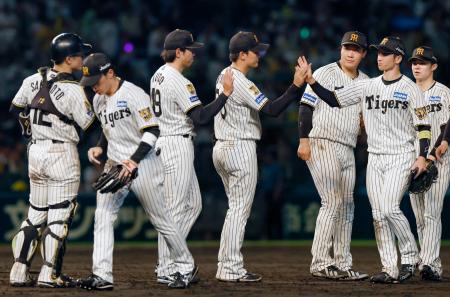 　巨人に勝利しタッチする阪神ナイン。優勝へのマジックナンバー「２３」が点灯した＝甲子園