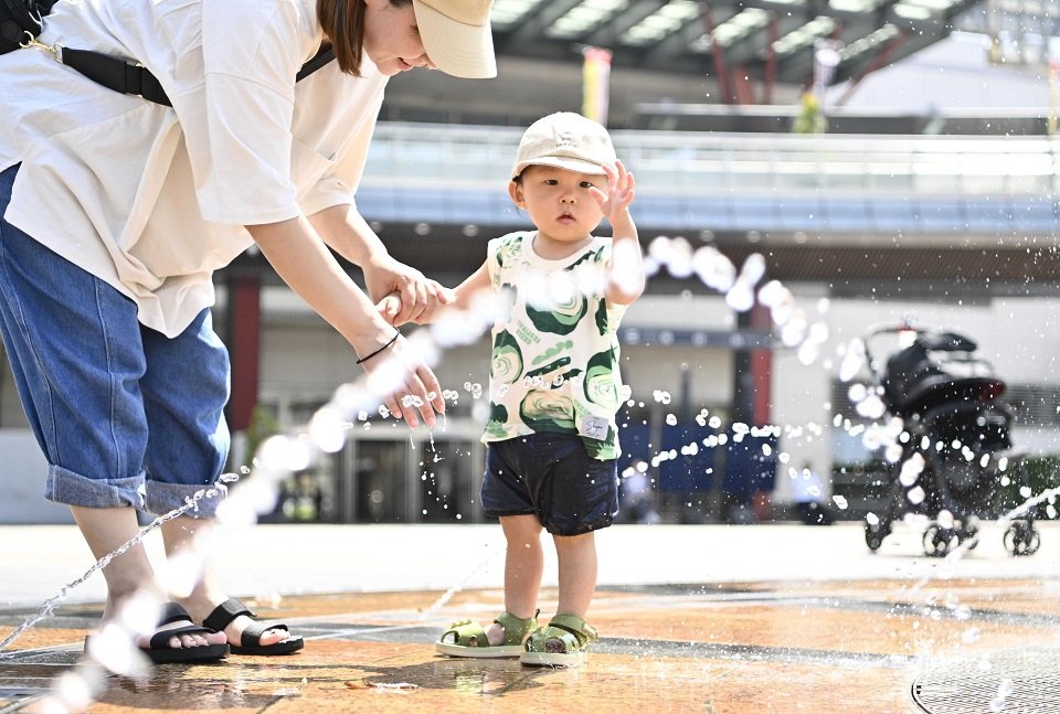 今年一番の暑さの中、噴水のしぶきで遊ぶ子ども＝１７日午後１時２８分、岐阜市橋本町、ＪＲ岐阜駅北口信長ゆめ広場