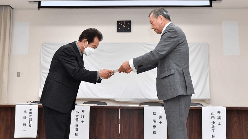 第三者調査委員会がまとめた調査報告書を牛嶋勝一副町長（左）に手渡す幅隆彦委員長＝岐阜県揖斐郡池田町役場