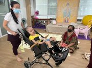 日本から贈られた車いすに乗るタイの子ども（中）＝タイ・バンコク、ノックホームスクール（安田さん提供）