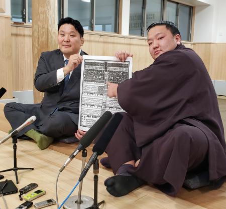　大相撲初場所の番付表を手にする朝白龍。左は高砂親方＝２２日、東京都墨田区の高砂部屋
