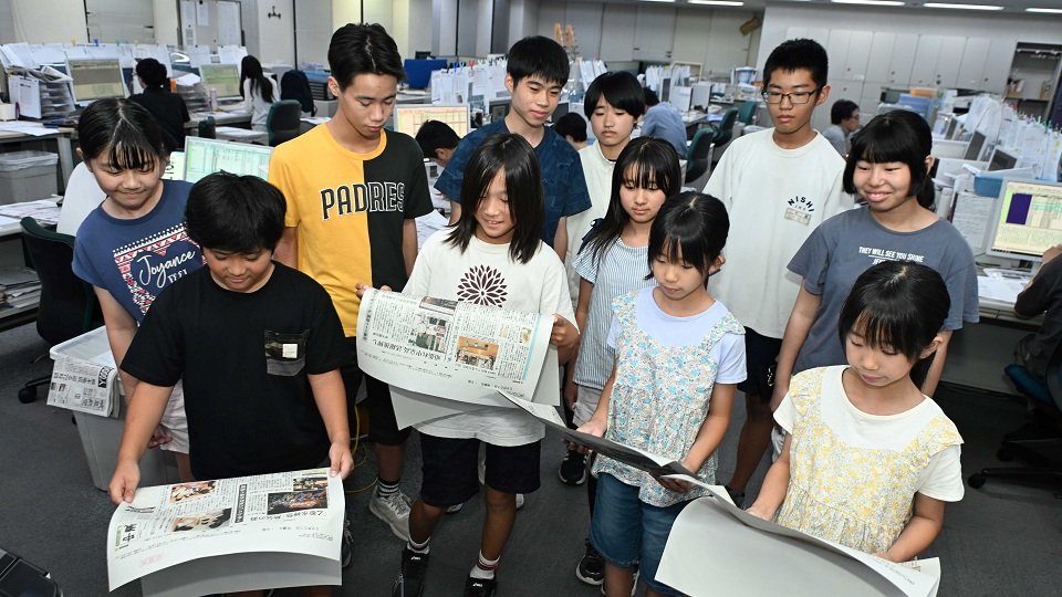 出来上がったばかりの紙面を見る参加者＝３１日午後９時８分、岐阜新聞本社
