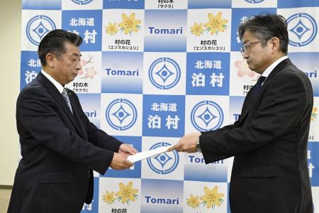 　資源エネルギー庁幹部から北海道電力泊原発３号機の再稼働に関する文書を受け取る北海道泊村の高橋鉄徳村長（左）＝４日午前、泊村役場