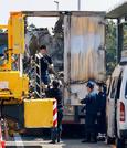 　炎上した大型トラックを調べる三重県警の捜査員ら＝３日午前、三重県菰野町
